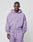 A man faces forward in a matching light purple LIVE FAST DIE YOUNG Basic Script Hooded Zip and sweatpants aus Baumwolle, featuring a small logo embroidery on the left chest. The plain background is light gray.