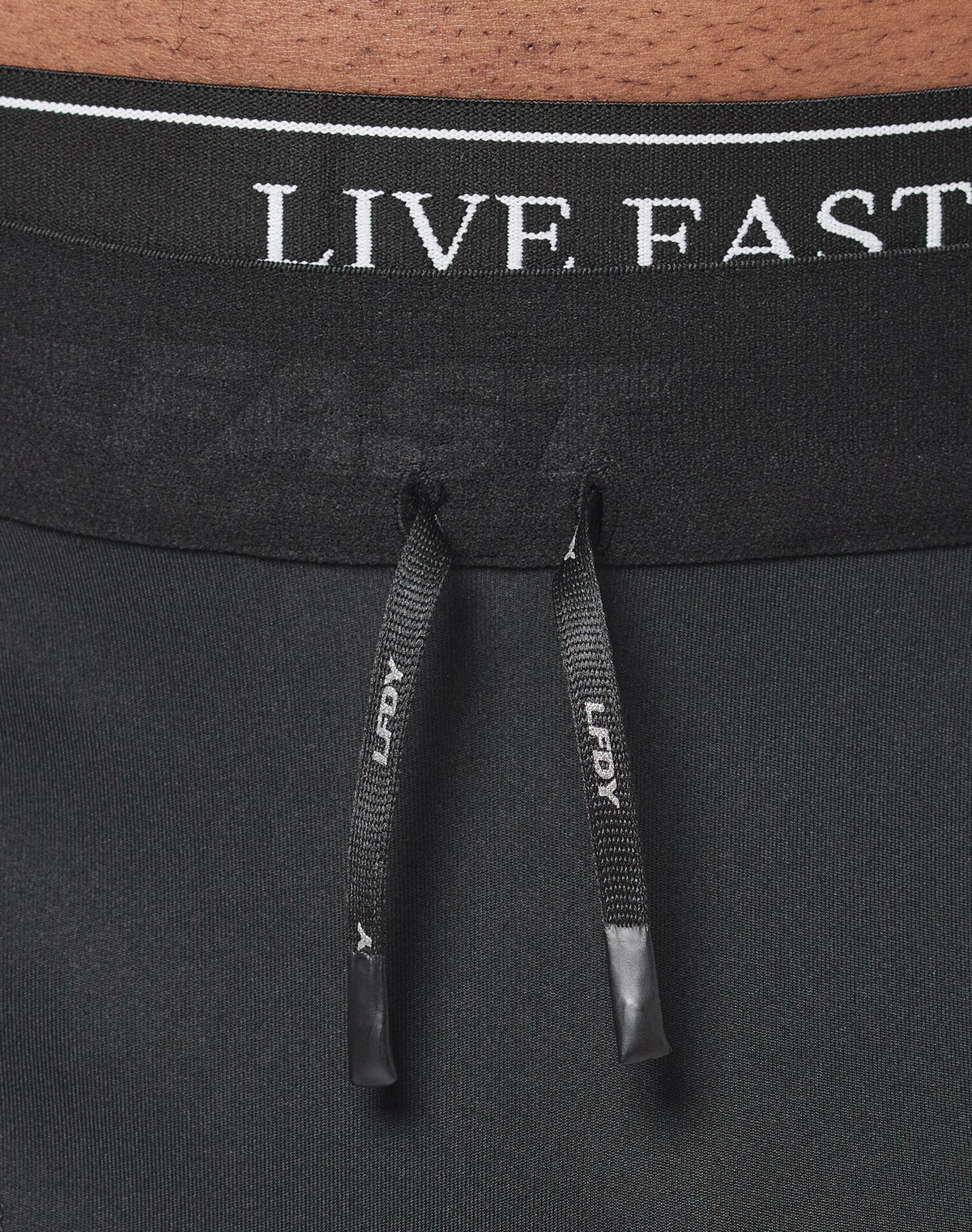 Close-up of the waistband on black Live Fast Performance Tights by LIVE FAST DIE YOUNG, featuring a comfortable Elastikbund, two black drawstrings with LEGACY in white, and partially visible Live Fast branding.| model 