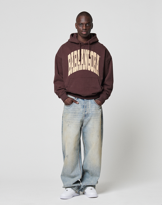 A person stands against a plain background wearing the LFDY x Baba Angora Hoodie by LIVE FAST DIE YOUNG, light blue baggy jeans, and white sneakers—a perfect streetwear look inspired by Berliner Stiftung style.