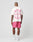 A man faces away, wearing the LFDY Loyal Tee by LIVE FAST DIE YOUNG—an oversized white t-shirt with pink front and back graphics reading LIVE FAST—paired with pink shorts, white socks, and sneakers, set against a light gray background.
