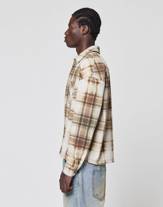 A person with braided hair stands in profile, wearing the LIVE FAST DIE YOUNG Faded Flannel in an oversize fit with light blue jeans against a plain white background.