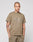 A tattooed man wears the LIVE FAST DIE YOUNG Live Fast Rhinestone Tee in an oversized khaki fit, paired with matching khaki pants. He stands facing forward with hands in pockets against a plain light background.