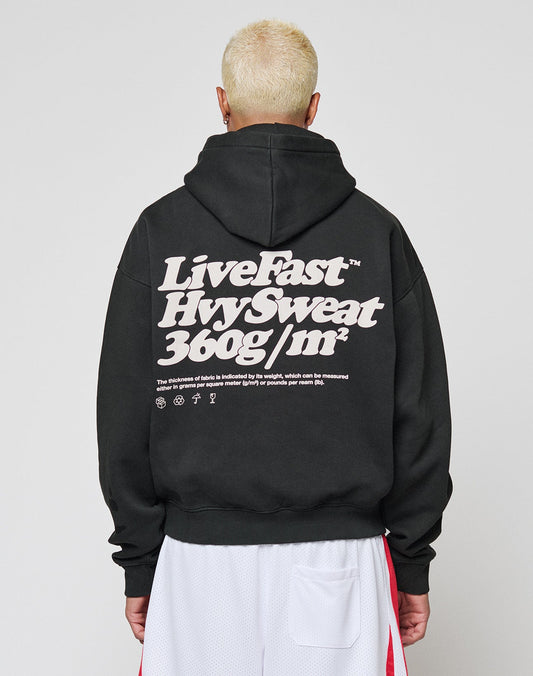 A person with short, bleached blonde hair wears the LIVE FAST DIE YOUNG Basic 360 Hooded in an oversize fit with bold white LiveFast text on the back, facing away from the camera over white athletic shorts.