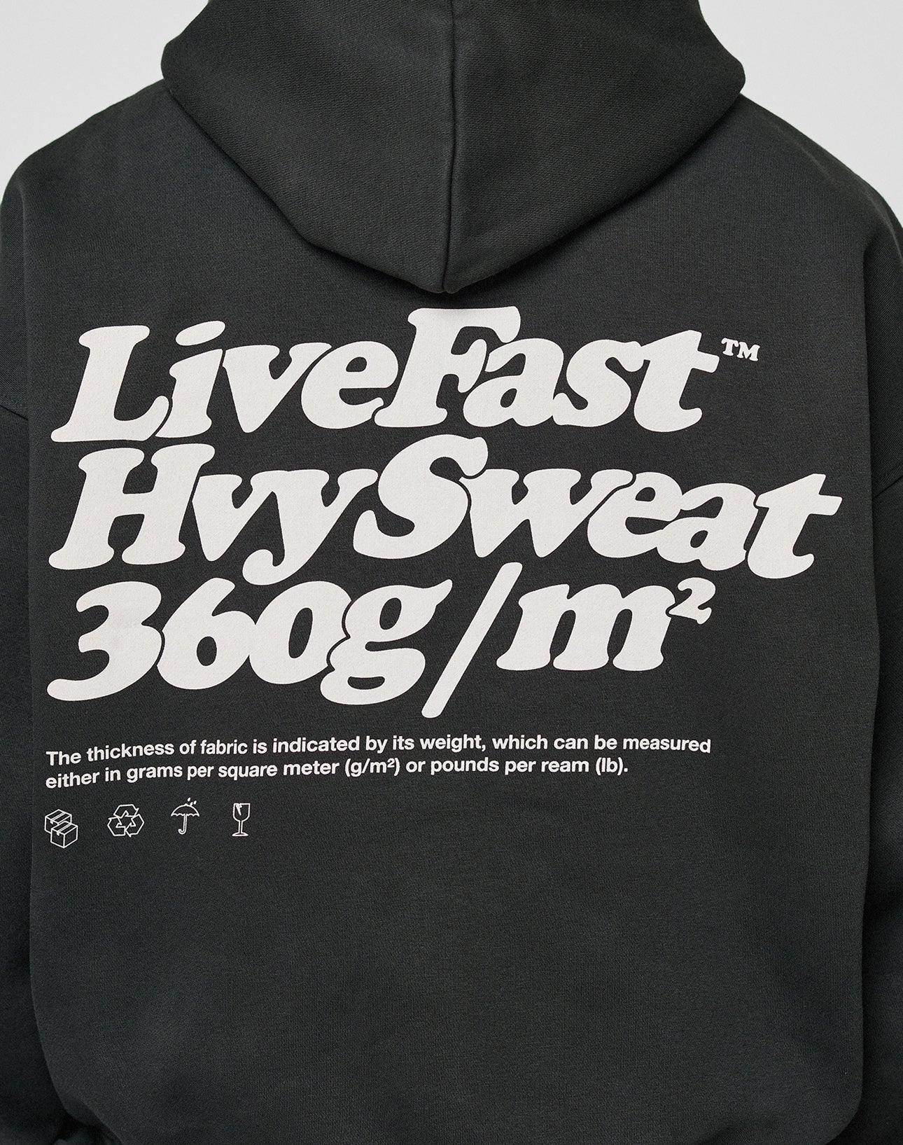 The LIVE FAST DIE YOUNG Basic 360 Hooded is a black oversize-fit hoodie with bold white “LiveFast HvySweat 360g/m²” text on the back, fabric details, care icons, topstitching for durability, and premium cotton (Baumwolle) material.
