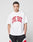 A person with short braided hair wears the LIVE FAST DIE YOUNG Live Fast College Tee, an oversize white t-shirt with bold red front letters, paired with black, white, and red shorts against a plain light gray background.