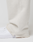A close-up of a person wearing LIVE FAST DIE YOUNG LFDY Heavyweight Loungepants in off-white with frayed hems and white sneakers, standing against a plain light background. The focus is on the lower leg and foot.