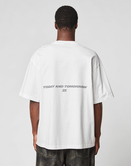 Someone wears the LFDY Trinity Tee by LIVE FAST DIE YOUNG—an oversize white 100% Baumwolle T-shirt featuring a gray reflective TODAY AND TOMORROW print on the back—against a plain light background.