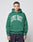 A person faces forward in an oversize fit, green LIVE FAST DIE YOUNG Live Fast College Hooded sweatshirt made from Baumwolle with a bold LIVE FAST frontprint, paired with dark jeans against a plain light background.