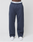 Someone stands against a plain light gray background wearing LIVE FAST DIE YOUNG LFDY Heavyweight Loungepants in navy blue 650gsm, wide fit, with a LIVE FAST waistband and white sneakers.