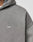 Close-up of a person wearing the LIVE FAST DIE YOUNG Basic Hooded Zip in faded gray with subtle distressing and a small white LFDY™ logo embroidered on the chest. The lightly cropped fit shows part of the shoulder and upper chest.