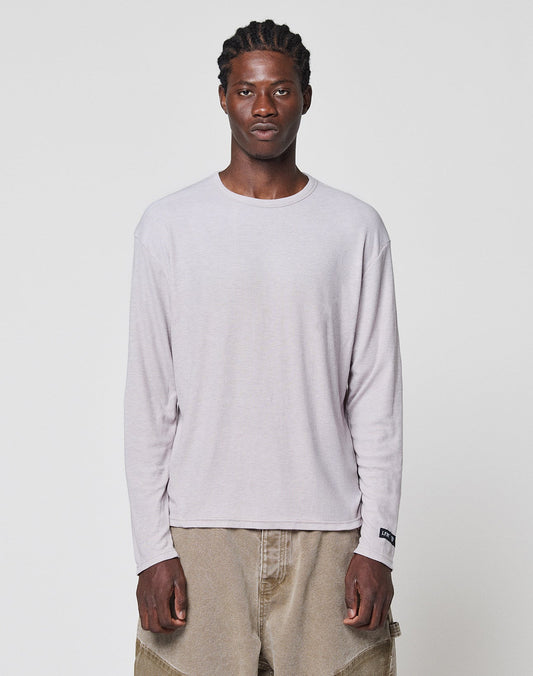 A man with braided hair wears the LIVE FAST DIE YOUNG LFDY Rib Longsleeve and loose tan pants, standing facing forward against a plain white background. | model