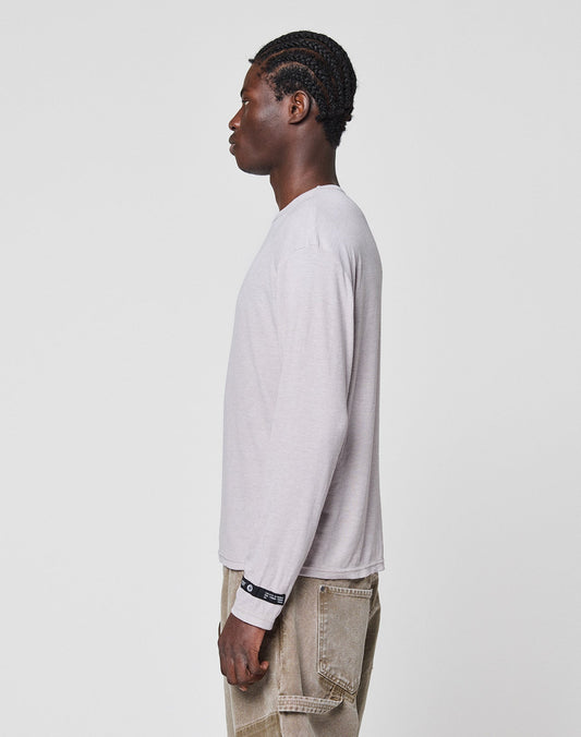 A person with braided hair stands in profile, facing left, wearing the LIVE FAST DIE YOUNG LFDY Rib Longsleeve in light gray and beige pants, set against a plain white background.