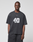 A man with short hair and a neutral expression stands against a light gray background, wearing the LIVE FAST DIE YOUNG LFDY 40 Tee—an oversize black t-shirt made from 100% cotton with a bold 49 and tiger graphic on the front.
