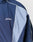 A close-up of the LIVE FAST DIE YOUNG Basic Nylon Trackjacket in navy and light blue, featuring white piping, side welt pockets, and Live Fast embroidered as a stylish logo on the chest.