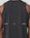 A close-up of a persons back in the Live Fast Performance Tank by LIVE FAST DIE YOUNG, a slim fit black sleeveless nylon-spandex shirt featuring LIVE and FAST in white, divided by a small reflective print at the center.