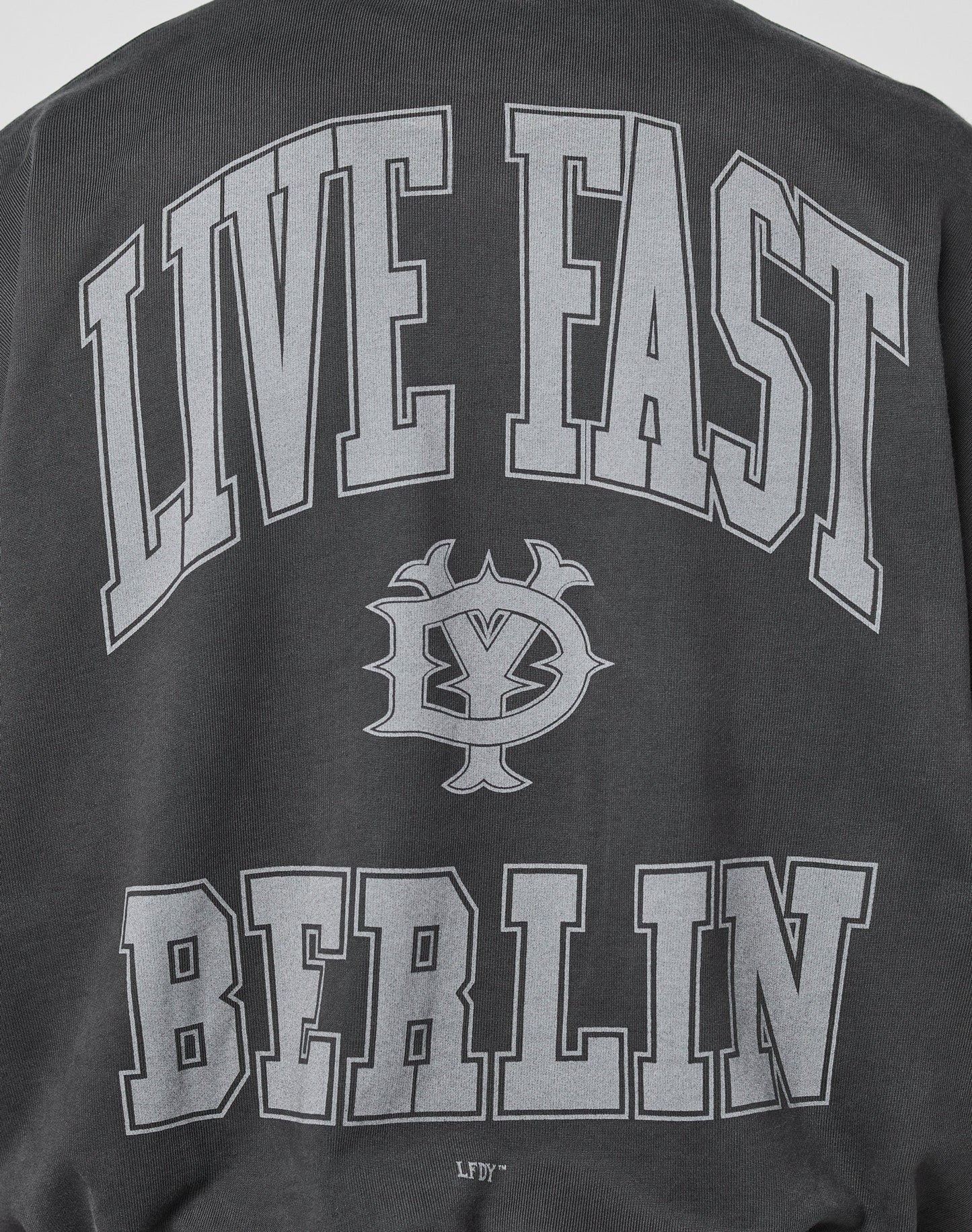 The Live Fast Berlin Sweater from LIVE FAST DIE YOUNG is a black, oversized sweatshirt with bold gray LIVE FAST text, a central graphic, BERLIN at the bottom, and quality topstitching for added style.