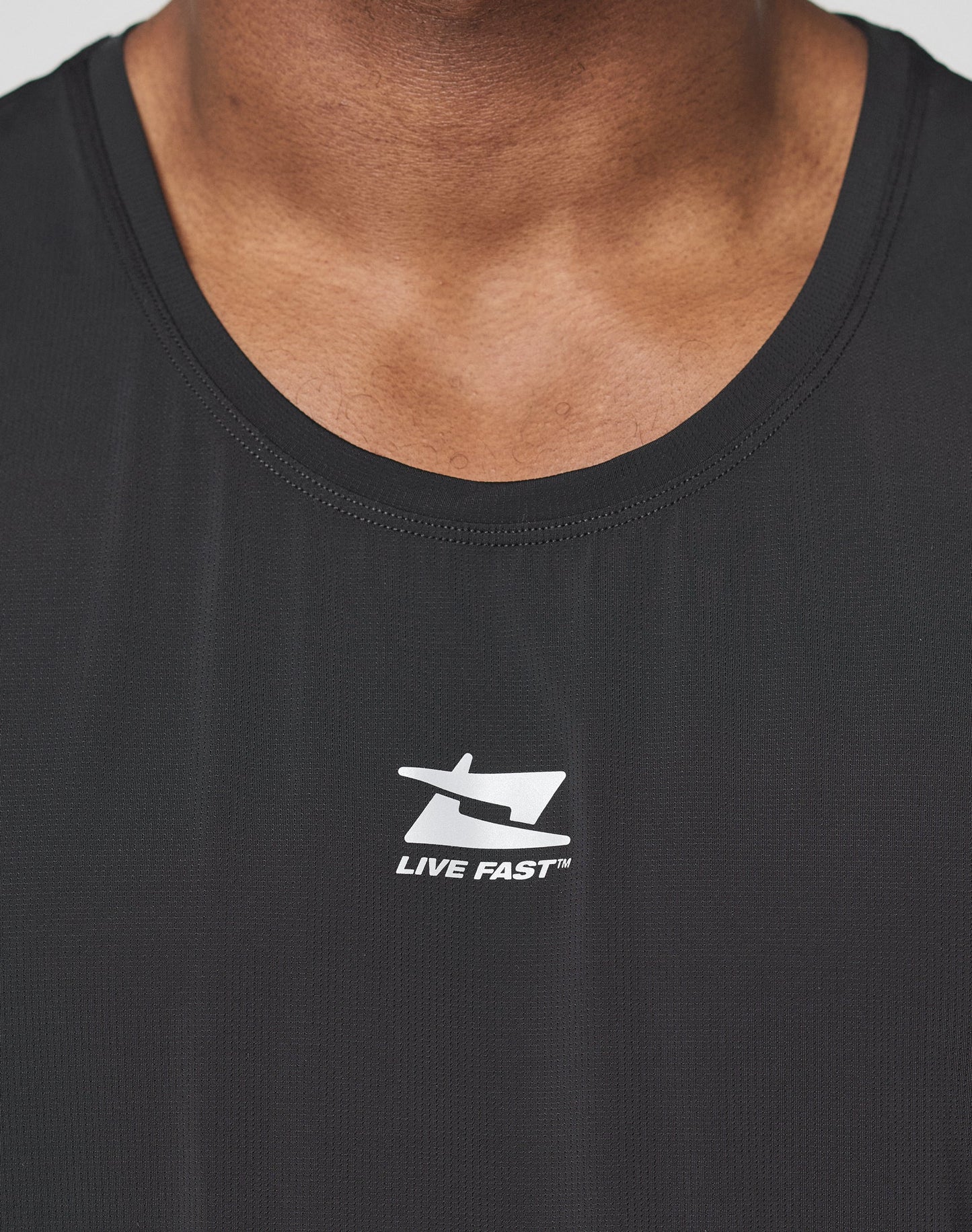The LIVE FAST DIE YOUNG Live Fast Performance Tank is a black, slim fit sleeveless top with soft fabric and "LIVE" and "FAST" in white capitals, separated by a small symbol, printed on the upper back.