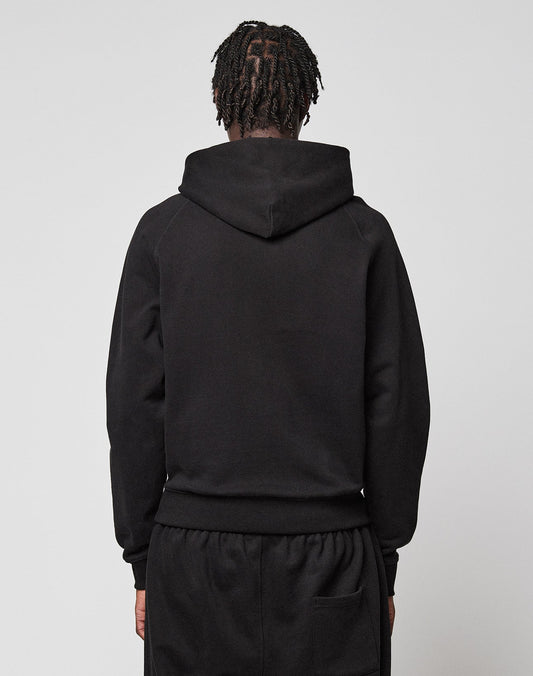 A person with braided hair stands with their back to the camera, wearing a black LFDY Embroidery Hooded by LIVE FAST DIE YOUNG and matching black pants against a plain light background.