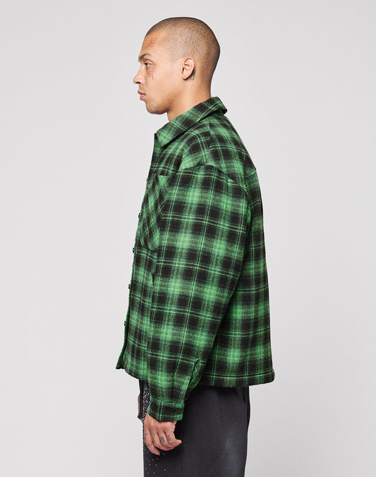 A person with short hair stands in profile facing left, wearing the LIVE FAST DIE YOUNG LFDY Padded Flannel and dark pants against a plain light gray background.