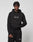 A young man with short braids models the LIVE FAST DIE YOUNG LFDY Embroidery Hooded and matching black sweatpants with white LiveVäst text, made from soft French terry, standing against a plain light gray background.