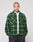 A person with a shaved head wears a green and black LIVE FAST DIE YOUNG LFDY Padded Flannel with chest pockets, layered over a white tee and black speckled pants, standing hands in pockets against a plain background.