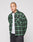 A person with a shaved head wears the green and black LIVE FAST DIE YOUNG LFDY Padded Flannel over a white t-shirt and black pants, standing against a plain light gray background.