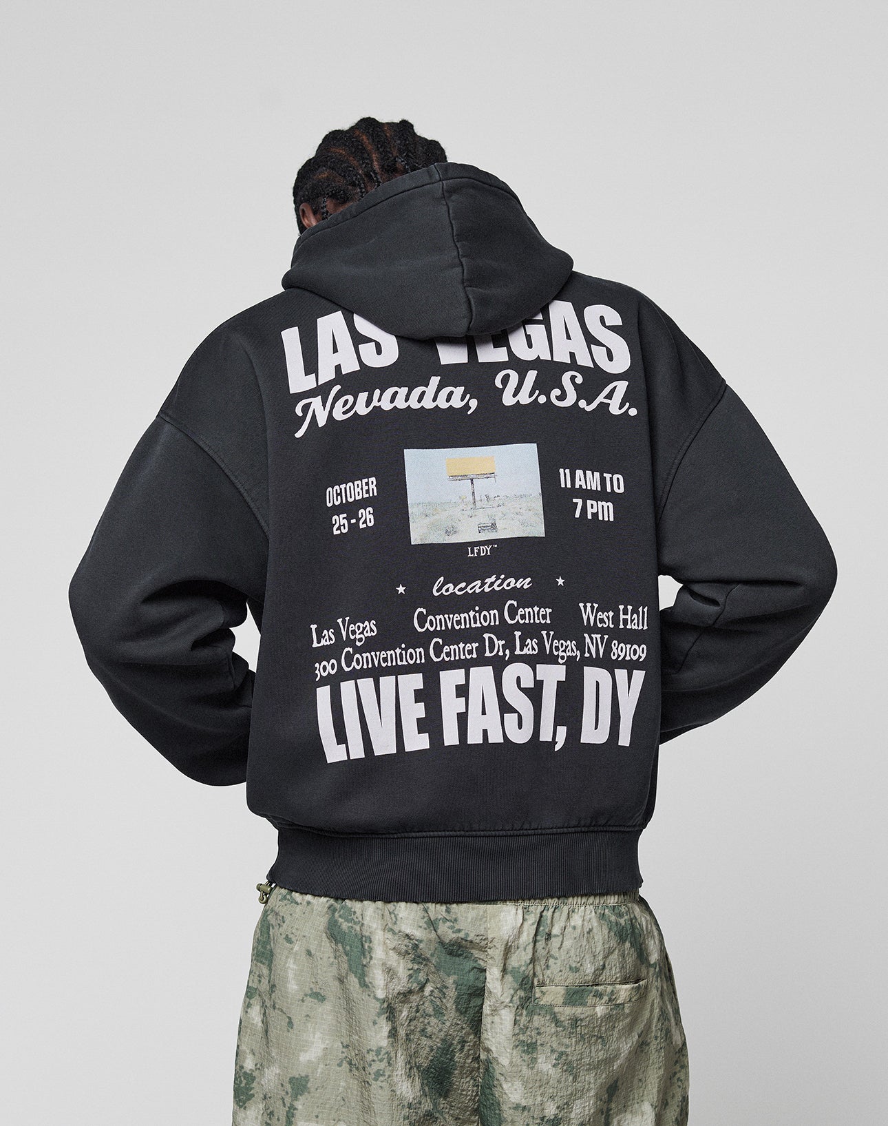 Someone in the Live Fast Vegas Hooded by LIVE FAST DIE YOUNG, an oversize-fit hoodie (65% Baumwolle) with bold front and back prints showing event details, dates, and "LIVE FAST, DIE YOUNG" in Las Vegas, Nevada.