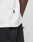 Close-up of a person wearing a white Basic LiveFast Tee by LIVE FAST DIE YOUNG, featuring a small black NOAH tag on the hem and paired with black pants. Torso, waist, and arm are shown, highlighting its Regular Fit style.