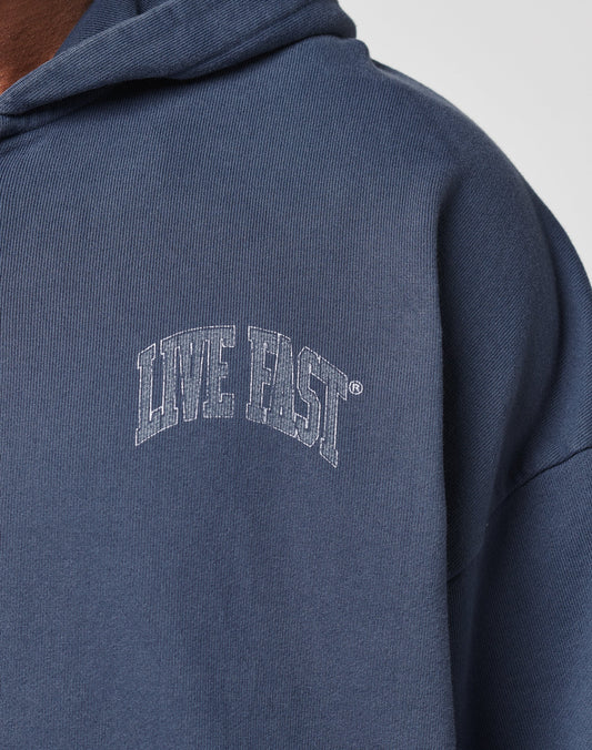A close-up of the Live Fast Berlin Hooded Zip by LIVE FAST DIE YOUNG, an oversized blue hoodie in soft cotton, featuring arched white LIVE FAST lettering on the chest.