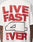 A person wears the LFDY 4 Ever Tee by LIVE FAST DIE YOUNG, an oversize white Baumwolle shirt with bold red LIVE FAST 4 EVER text and a large black-outlined number 4 printed on both front and back.
