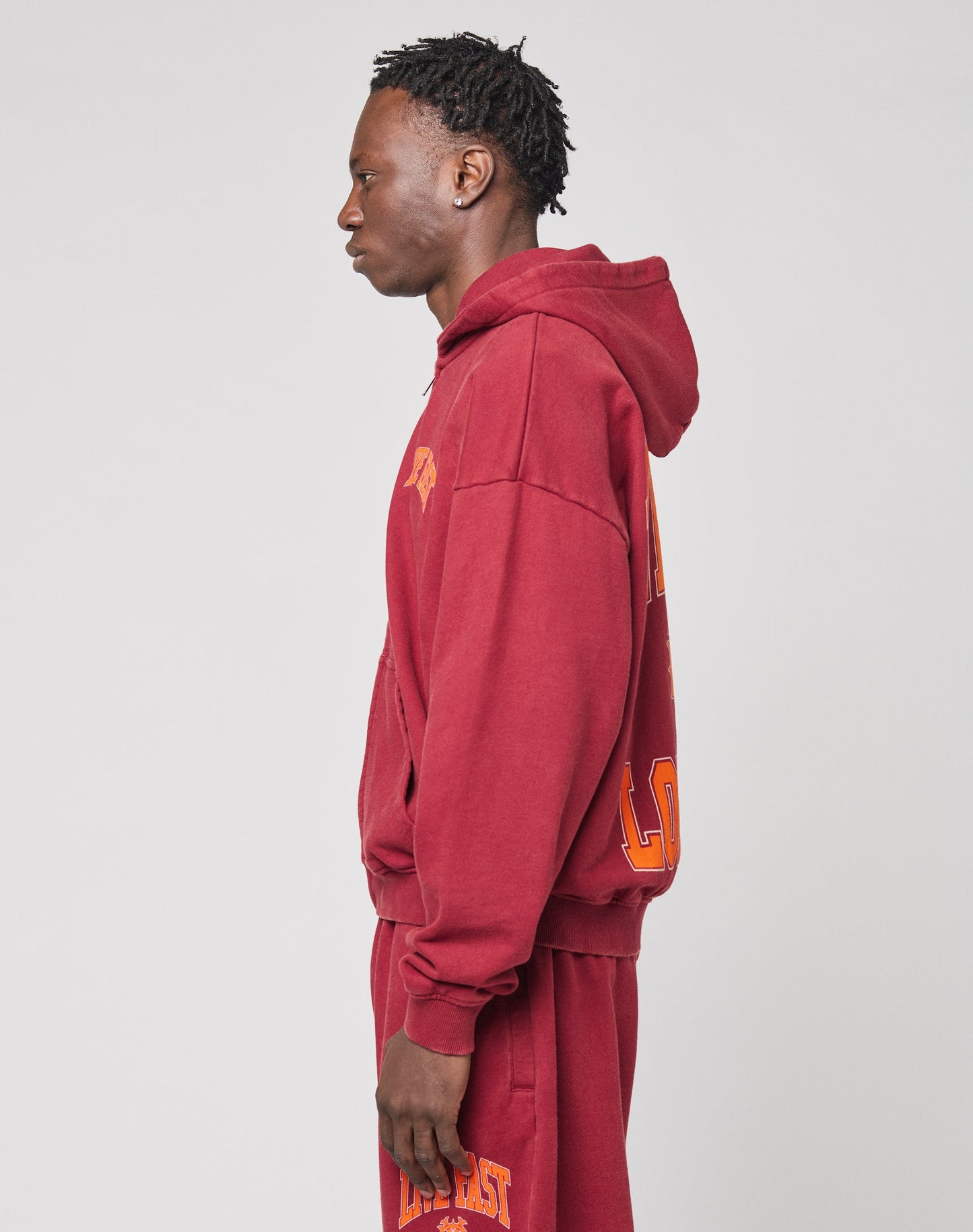 The Live Fast London Hooded Zip by LIVE FAST DIE YOUNG is an oversize maroon hoodie with bold yellow-orange LIVE FAST on the back, a center logo, and LONDON at the bottom, crafted from soft Baumwolle for all-day comfort.