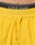 Close-up of LIVE FAST DIE YOUNG branding on the waistband of Live Fast Performance Running Shorts in bright yellow, featuring matching yellow drawstrings and partial view of a persons lower abdomen.