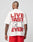 A person in red shorts is seen from the back, wearing a white LIVE FAST DIE YOUNG LFDY 4 Ever Tee featuring an oversize fit and bold red and black LIVE FAST 4 EVER text as a backprint.