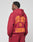 A person faces away from the camera in an oversize maroon LIVE FAST DIE YOUNG Live Fast London Hooded Zip, featuring bold orange LIVE FAST LONDON text on the back, set against a plain light background.