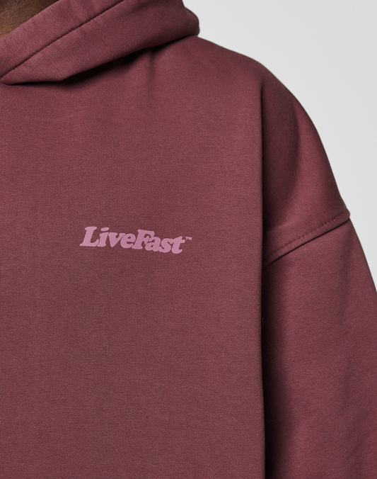 A close-up of the maroon Basic 360 Hooded by LIVE FAST DIE YOUNG, featuring "LiveFast" in light pink on the chest. This oversize fit hoodie is made from soft Baumwolle and includes a hood with visible seams.