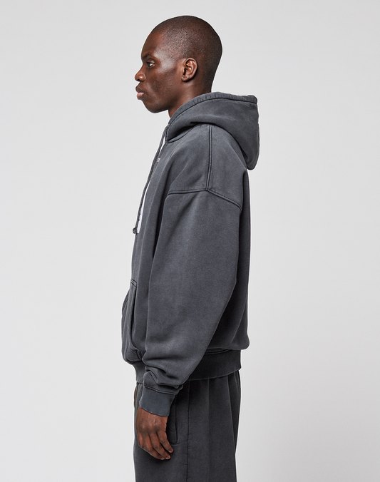 A person stands in profile facing left, wearing the LIVE FAST DIE YOUNG LFDY 40 Hooded sweatshirt and matching sweatpants with Kangaroo-Tasche, made from cotton-polyester blend, against a plain light background.