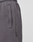 Close-up of a person wearing Live Fast LF Shorts by LIVE FAST DIE YOUNG in dark gray with side pockets, wide fit, and a small black LOUT tag near the pocket. An elastic waistband offers comfort. Background is plain and light-colored.