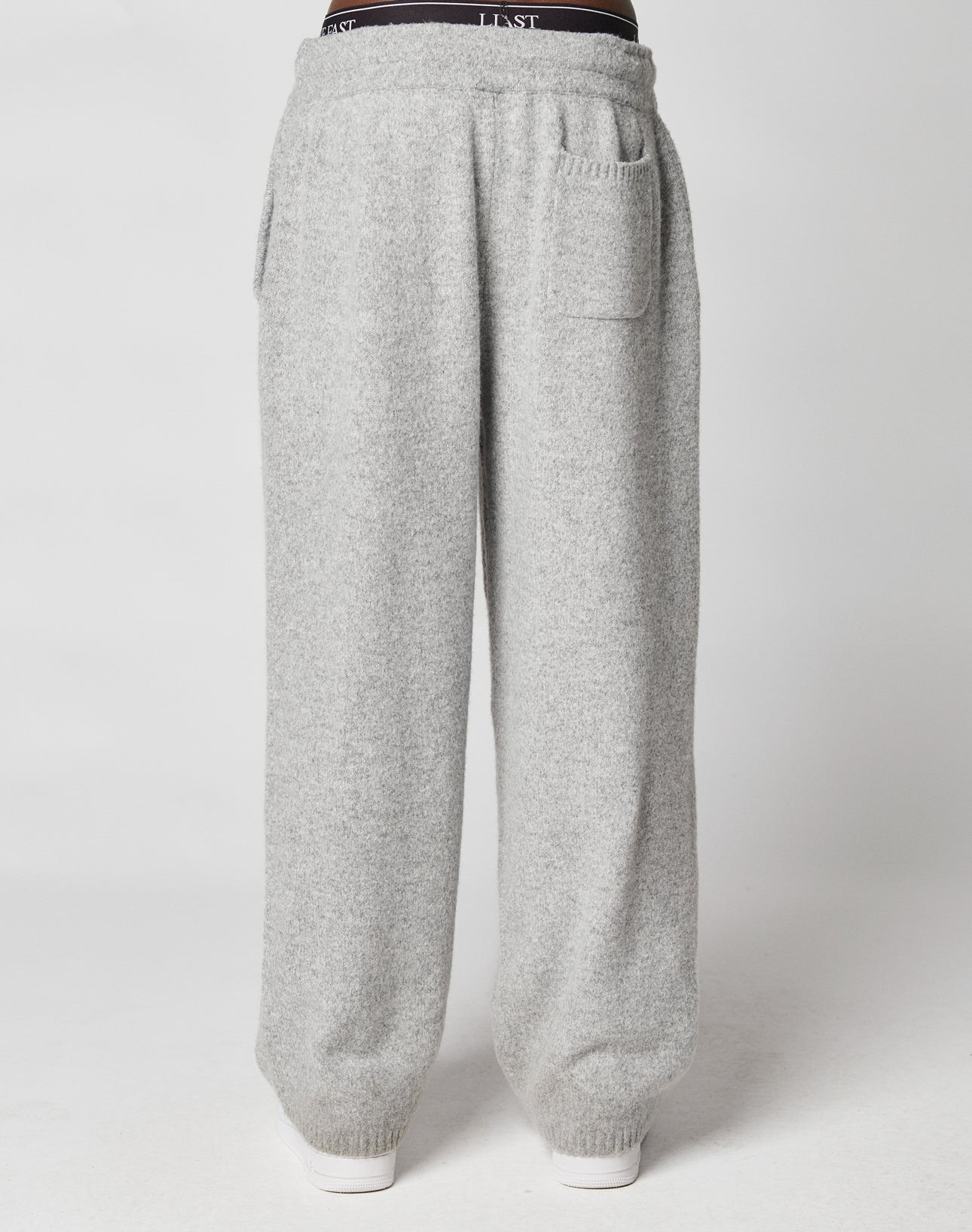 A person wearing LIVE FAST DIE YOUNG Live Fast Boucle Pants in a wide fit and light gray color with an elastic waistband and front pockets, standing against a plain white background.