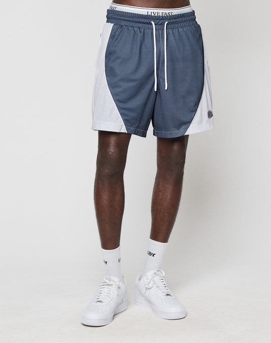 A person stands against a plain white background wearing LIVE FAST DIE YOUNG LFDY Piping Mesh Shorts in blue and white with a regular fit, elastic waistband, drawstring, and mesh side panels. Only the lower body is visible; socks and sneakers are white.