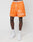 A person wears LIVE FAST DIE YOUNG LFDY Praying Mesh Shorts in orange, with a white praying hands and cross graphic, elastic waistband, and polyester fabric, paired with white athletic socks and sneakers against a plain background.