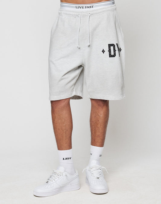 Someone wears DY Rivet Shorts by LIVE FAST DIE YOUNG in light gray with an oversize fit, black DY logo, white LIVE FAST waistband, LF DY socks, and white sneakers. The outfit is made from 100% Baumwolle, set against a plain white background.