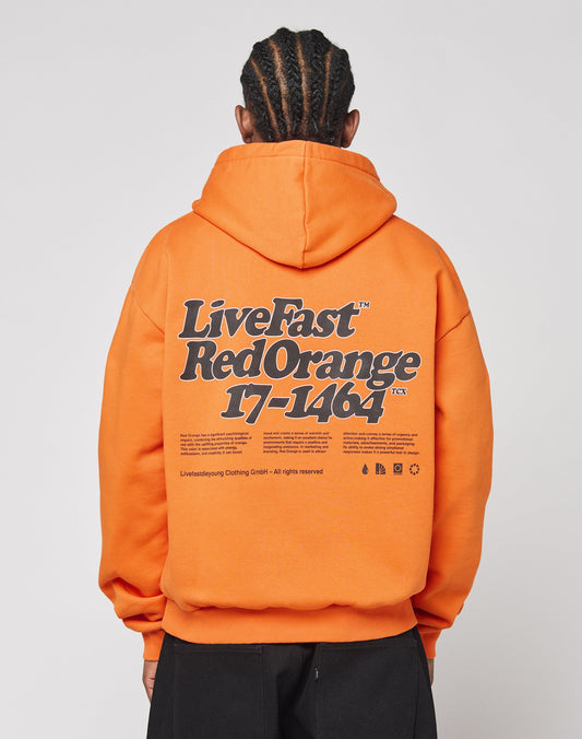 A person with braided hair wears the Basic Orange Hooded by LIVE FAST DIE YOUNG, made of polyester and cotton, featuring a bold black and white Live Fast Red Orange 17-1464 front and back print plus extra small text and symbols. | model