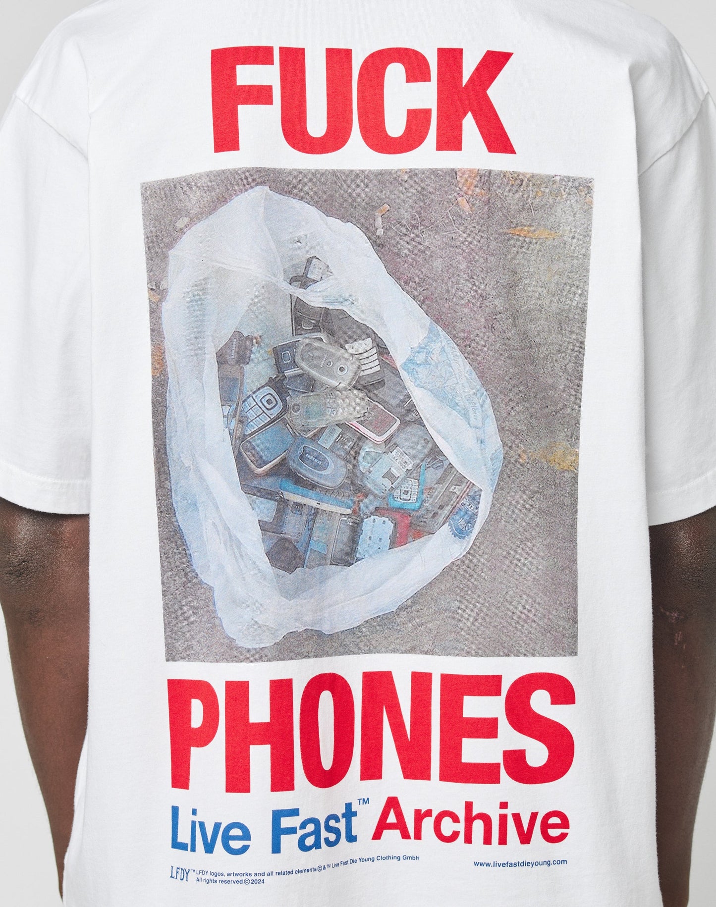 The LFDY F*ck Phones Tee by LIVE FAST DIE YOUNG is a white oversized Baumwolle T-shirt featuring a front print of a plastic bag with old cell phones, bold red FUCK text above, PHONES below, and Live Fast Archive in blue and red.