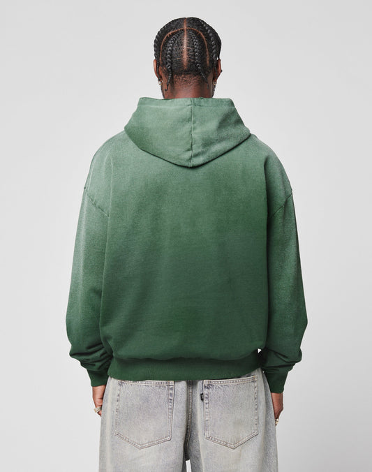 A person with braided hair is seen from behind, wearing the LIVE FAST DIE YOUNG LFDY Script Hooded in an oversize fit and light-wash jeans, set against a plain light gray background.
