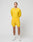 A man stands before a light background in a slim-fit yellow Live Fast Performance Longsleeve by LIVE FAST DIE YOUNG and matching shorts with mesh inserts, paired with white socks and sneakers. His hands are behind his back, expression neutral.