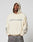 A person wears the LIVE FAST DIE YOUNG LFDY Window Hooded, a cream, oversize hoodie with LIVE FAST on the front, reflektierender Druck on the sleeves, hands in pocket, and hood up for a bold look.