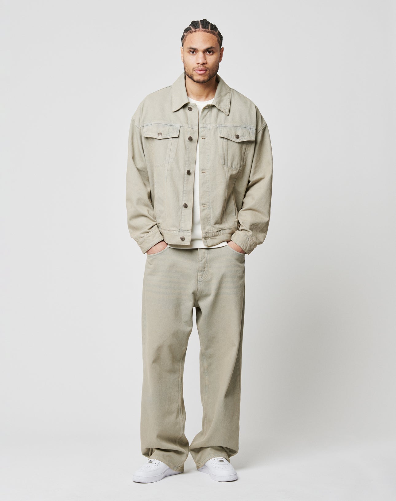 A man stands facing forward with hands in pockets, wearing the LIVE FAST DIE YOUNG LFDY Baggy Denim set in light beige and white sneakers, against a plain white background.