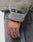 A close-up of a hand with “TIME” tattooed on the fingers, wearing grey jeans and an oversized beige LIVE FAST DIE YOUNG LFDY Teddy Hooded fleece with a black LFDY web label on the sleeve.