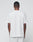 A person with short hair stands with their back to the camera, wearing a plain white LIVE FAST DIE YOUNG Basic Chest Tee in 100% Baumwolle and light-colored shorts, set against a neutral background.