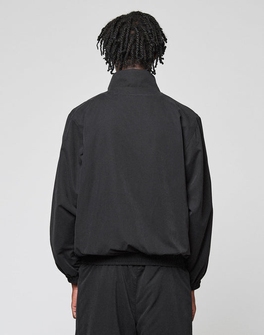 A person with short, twisted hair is seen from behind wearing the black LFDY Trackjacket by LIVE FAST DIE YOUNG with logo-stick details and matching oversized black pants, set against a plain light background.